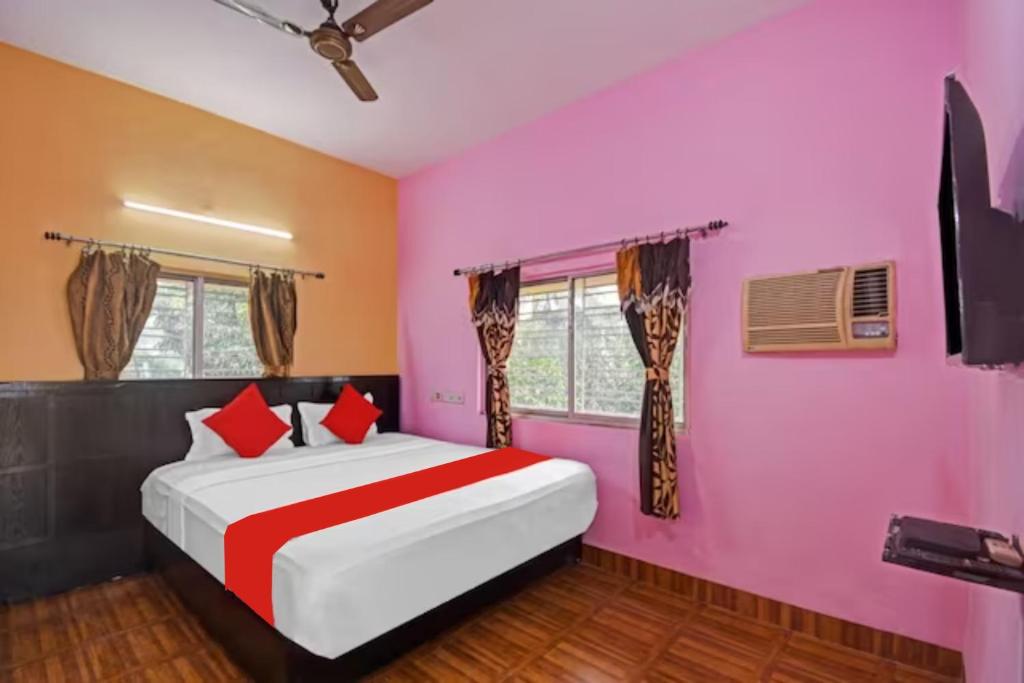 コルカタにあるHotel Salt Lake Palace Kolkata Sector II Near Dum Dum Park - Fully Air Conditioned and Spacious Room - Couple Friendlyのピンクの壁のベッドルーム1室、赤い枕付きのベッド1台が備わります。