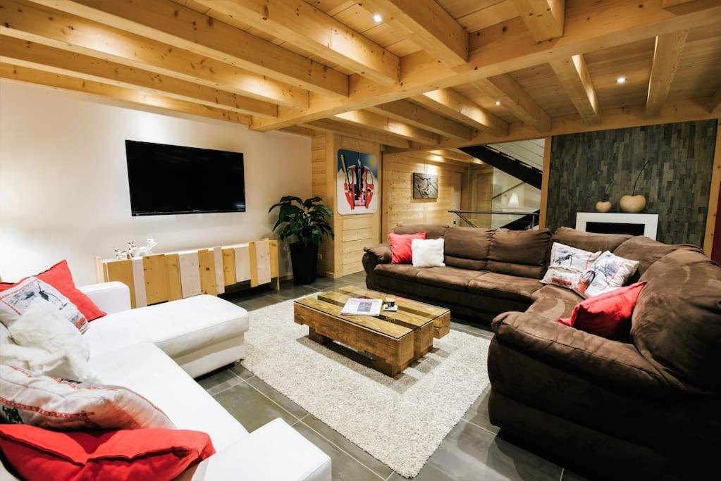 a living room with couches and a flat screen tv at The Alpine Lodge in Les Gets