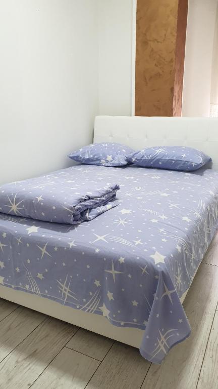 a bed with a blue comforter and pillows on it at Apartmani Borko 1-2 in Loznica