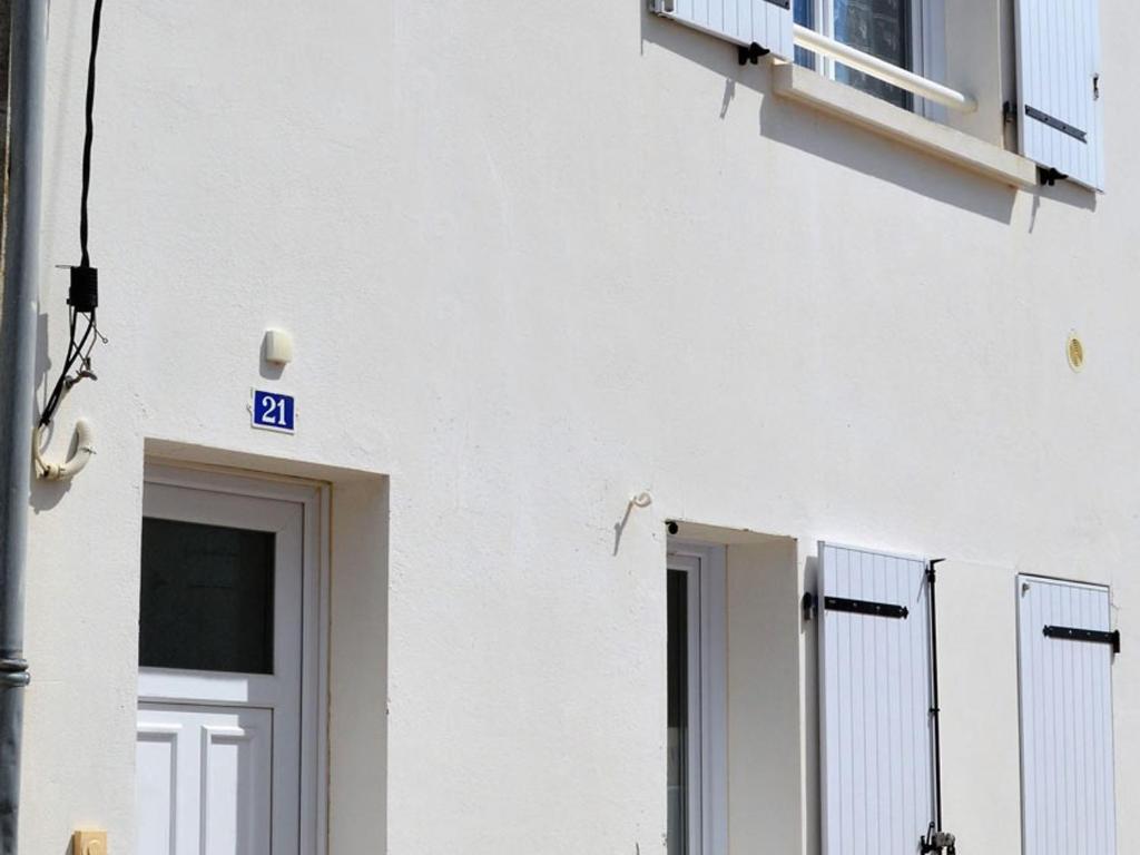 ein weißes Gebäude mit einer Tür und einem Balkon in der Unterkunft Maison La Tranche-sur-Mer, 2 pièces, 4 personnes - FR-1-22-256 in La Tranche-sur-Mer