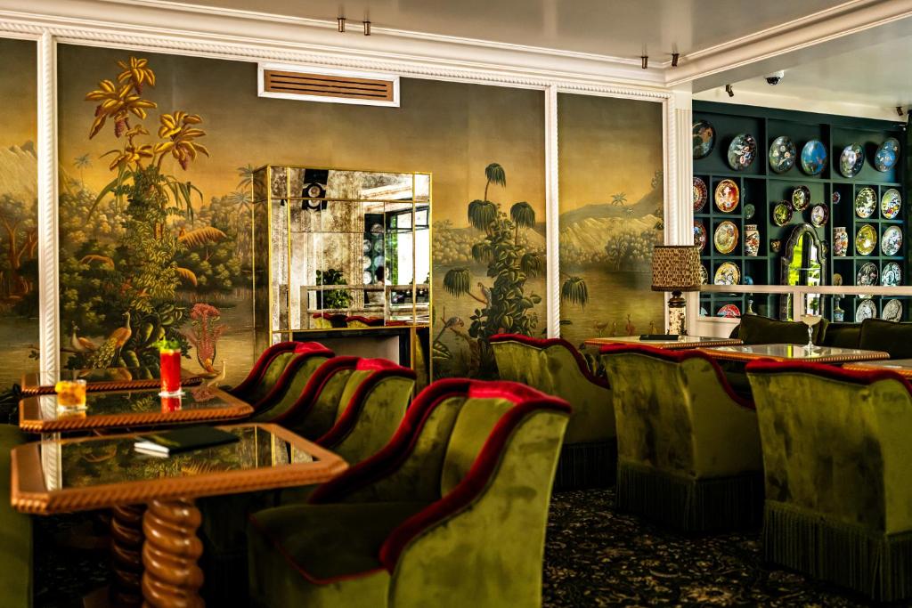 a restaurant with green chairs and a table and a painting at Hôtel Eldorado Paris in Paris