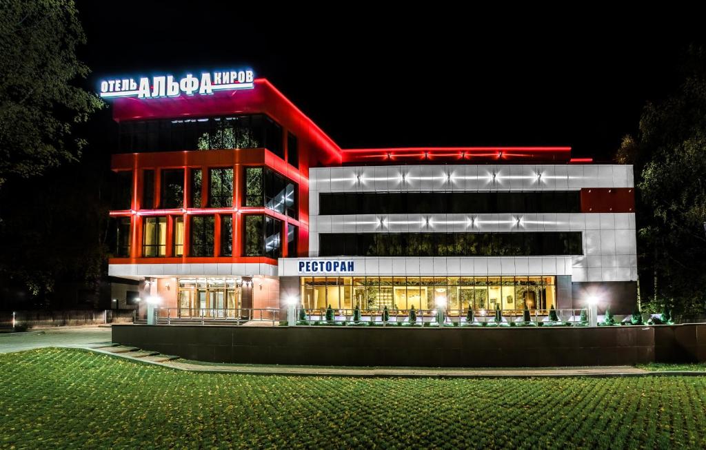 un edificio con un letrero iluminado delante de él en Alpha Business-Hotel, en Kirov