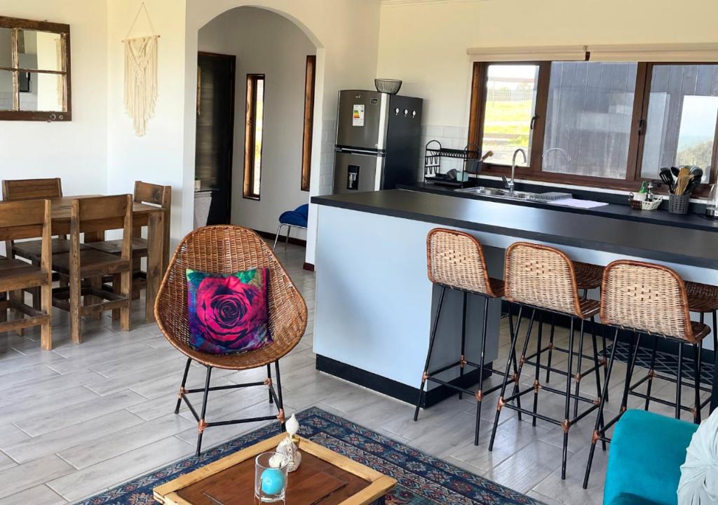 a kitchen with a counter and some chairs and a table at Casa Catrianca, Punta de Lobos in Pichilemu