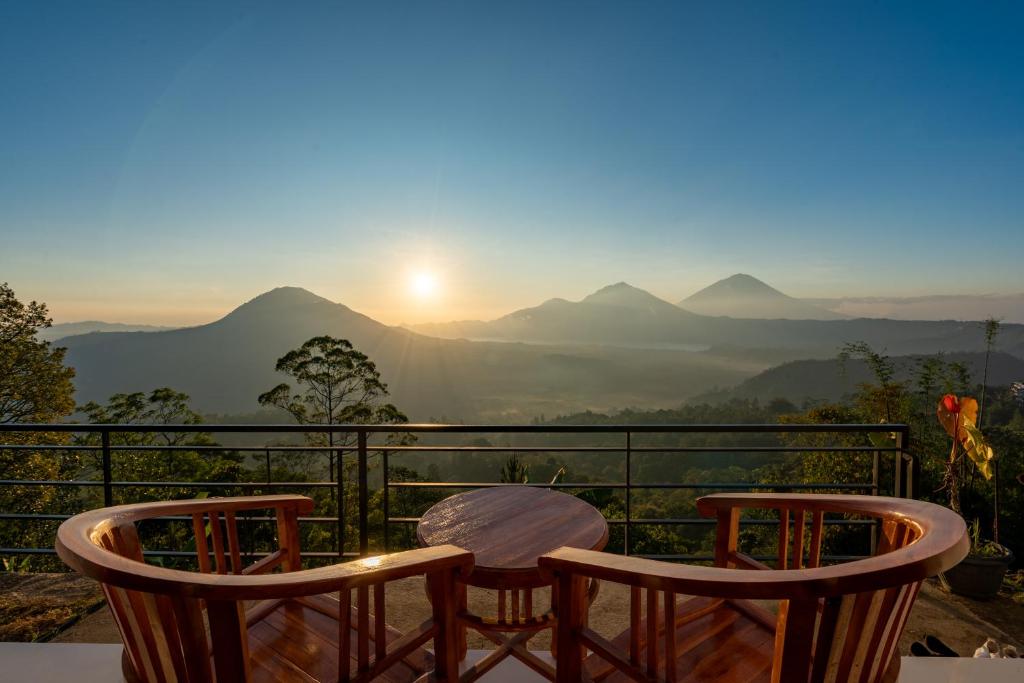 a table and chairs on a balcony with a view of mountains at Tegal Sari Cabin Kintamani in Kintamani