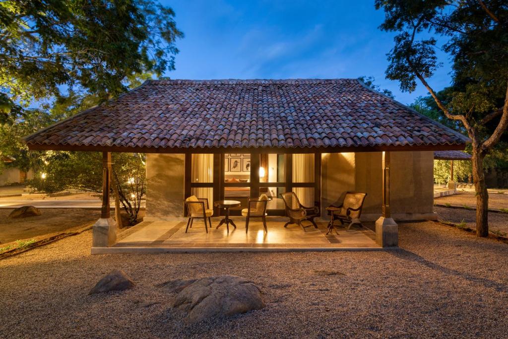 um pavilhão com cadeiras e uma mesa em frente a uma casa em Koragaha Lodge - Yala em Tissamaharama