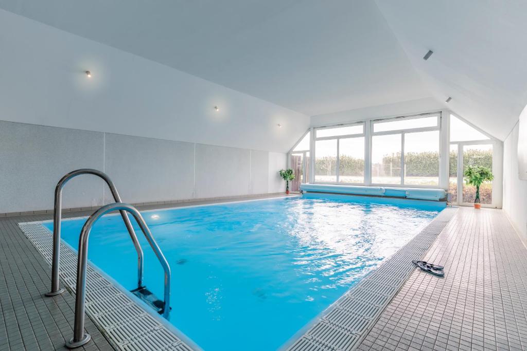 a large indoor swimming pool with blue water at Die Ostseeperle mit Pool 2 in Barendorf