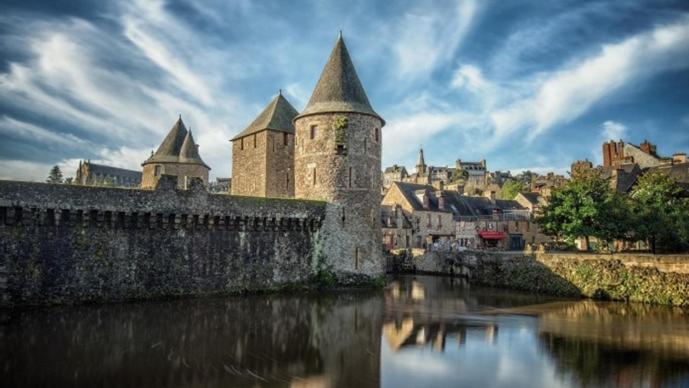 a castle sitting next to a river in a city at Gîte Pontors&#39;home Mont Saint-Michel in Pontorson