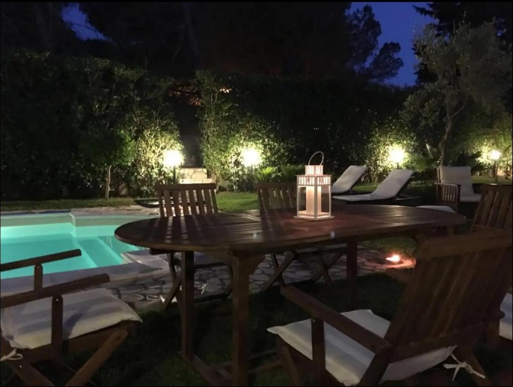 a wooden table and chairs next to a pool at night at Villa Cavagrande in Avola