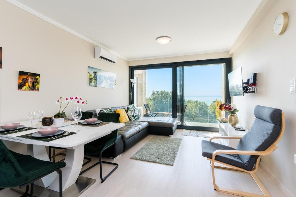 a living room with a couch and a table and chairs at Club Panorama Lake View Apartment in Alsóörs