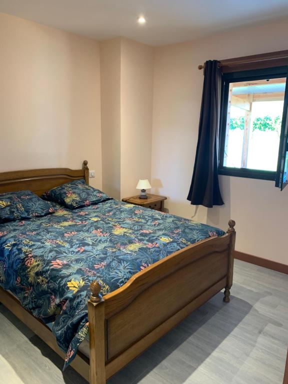 a bedroom with a bed with a blue comforter and a window at Gîte du Busatier in Marcillac-la-Croisille