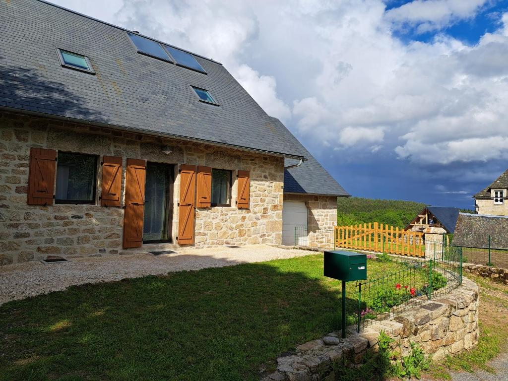 a stone house with a yard and a fence at Gîte du Busatier in Marcillac-la-Croisille