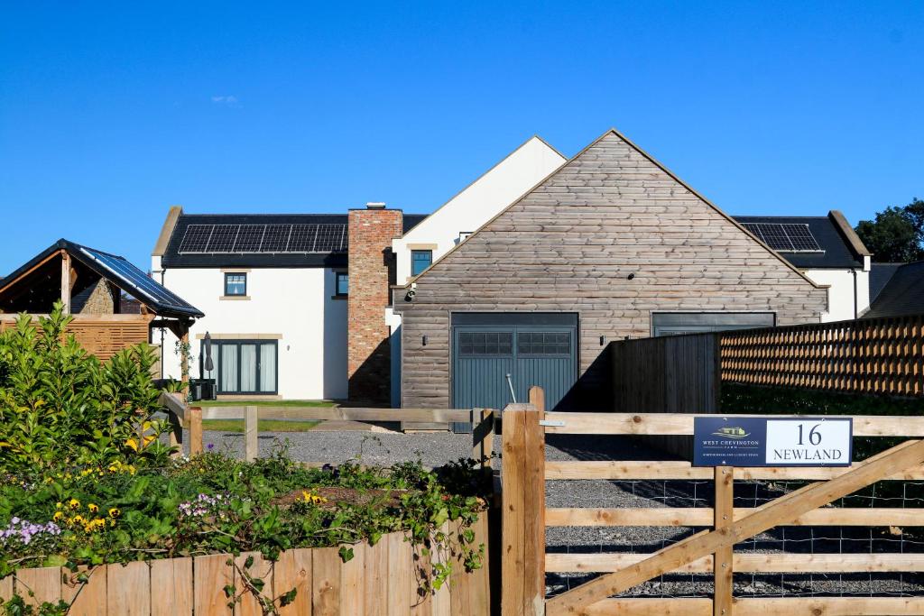 a house with a wooden gate and a fence at Northumberland Luxury Stays - The Newland in West Chevington
