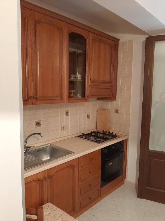 a kitchen with wooden cabinets and a sink and a stove at L'Isola nel Mare in San Vito lo Capo