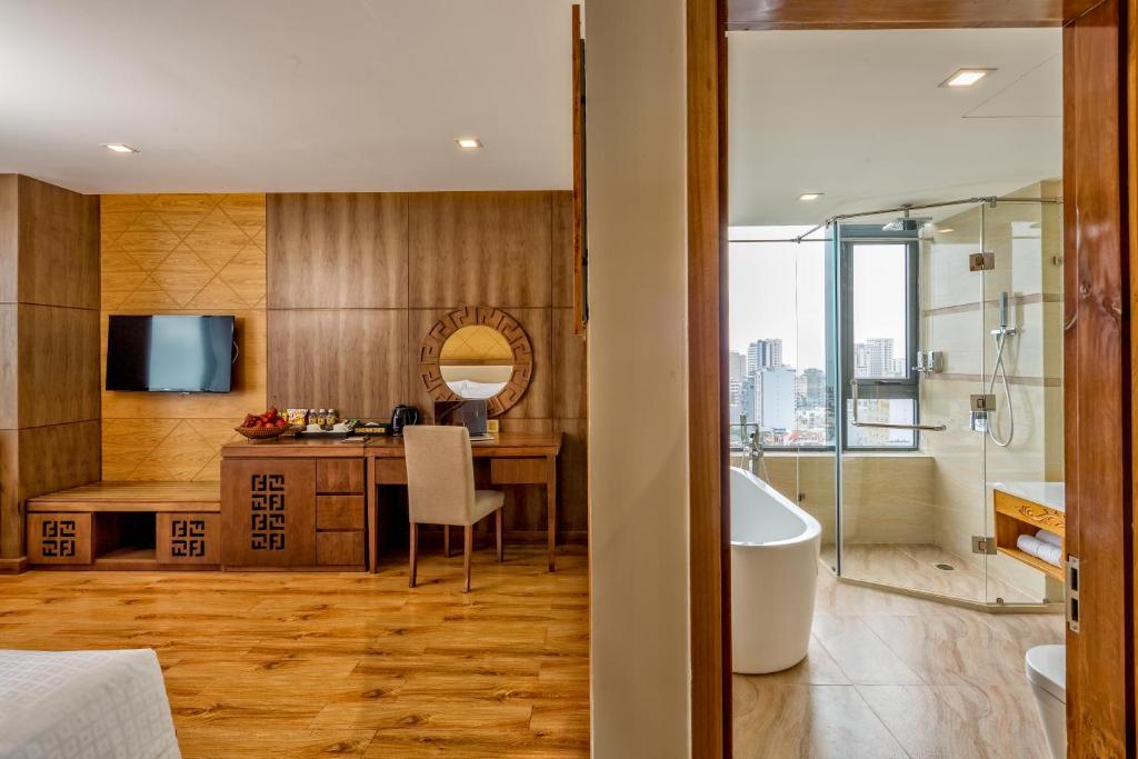 A bedroom-to-bathroom view showing a TV console, desk and freestanding bathtub.