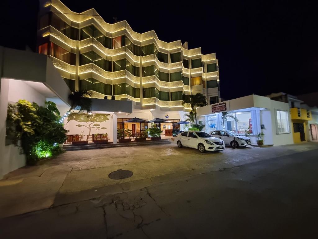 a building with cars parked in a parking lot at night at Hotel Plaza Cozumel in Cozumel