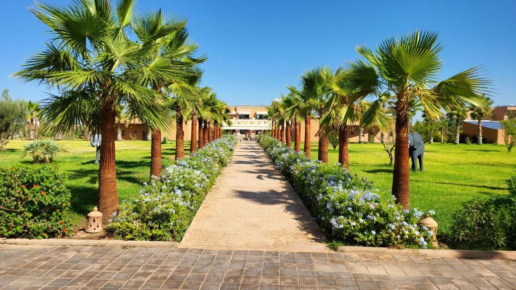 a path in a park with palm trees and flowers at Hôtel Jardins de lina et lea in Marrakesh