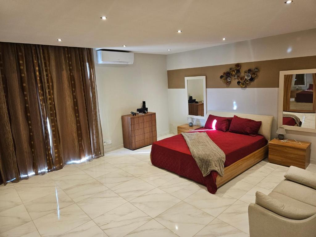 1 dormitorio con cama roja y sofá en Double bedroom in shared Penthouse Apartment - Seabreeze Terraces, en St Paul's Bay