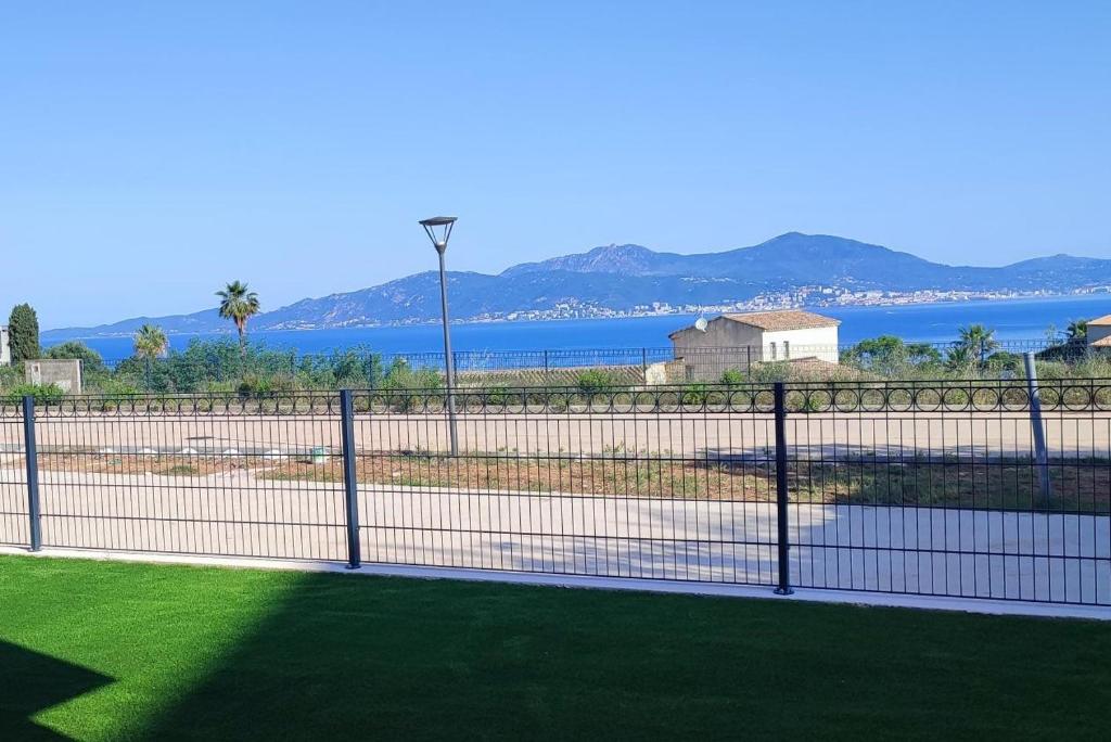 une clôture devant un champ avec une masse d'eau dans l'établissement T3 neuf, vue mer, à Pietrosella