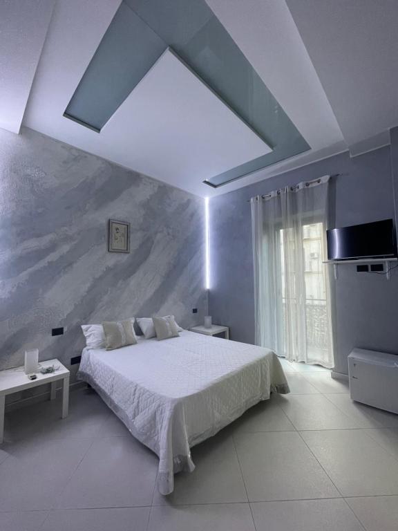 um quarto com uma cama branca e uma grande janela em Marisan em Porto Empedocle