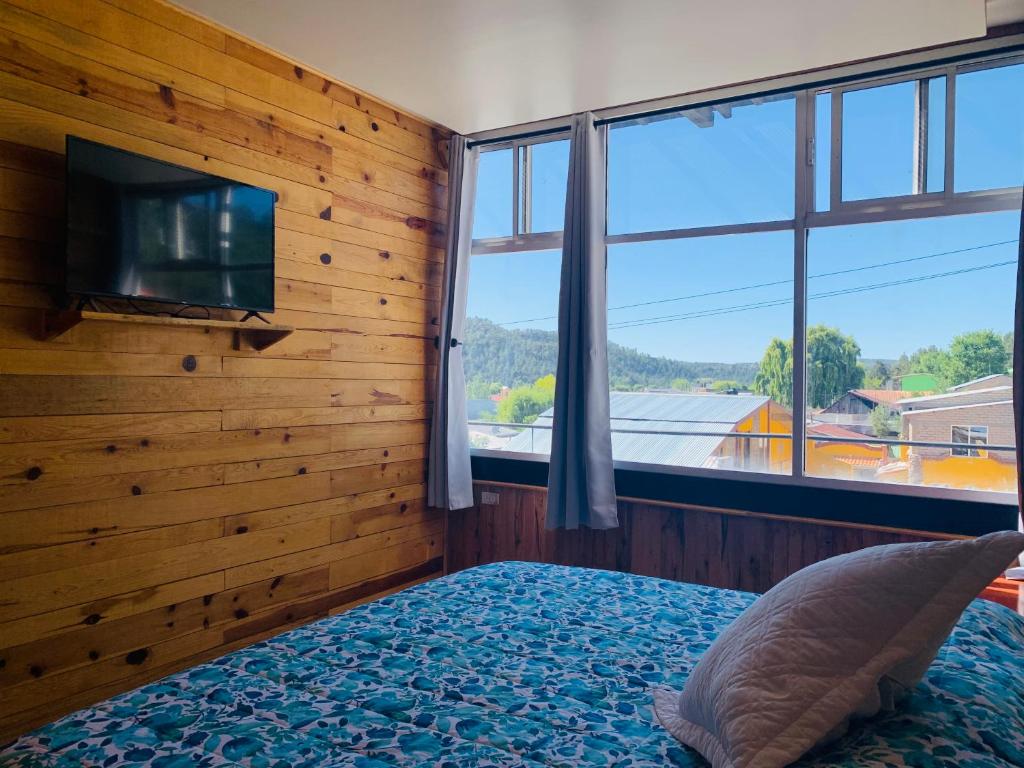 een slaapkamer met een houten muur, een tv en een bed bij Parque Cueva de los Leones - Rimusa Inn in Creel