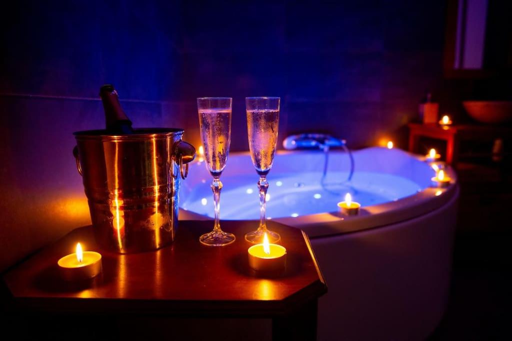 zwei Champagner-Gläser auf einem Tisch neben einer Badewanne mit Kerzen in der Unterkunft Bulle Romantique . Jacuzzi . Châteaux de la Loire in Vouvray