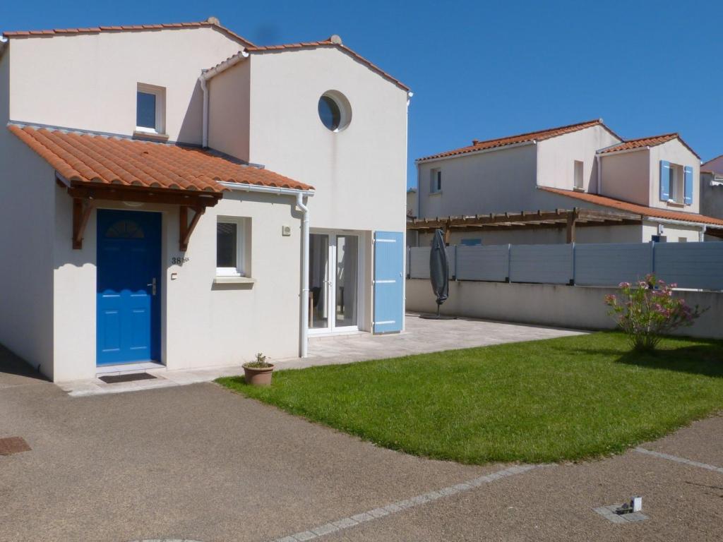 une maison blanche avec une porte bleue et une cour dans l'établissement Charmante maison rénovée avec terrasse, proche mer, La Tranche-sur-Mer, 6 pers, Wifi, parking. - FR-1-194-224, à La Tranche-sur-Mer