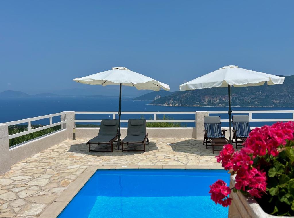 a swimming pool with chairs and umbrellas and flowers at Villa Fiscardo View Fiscardo Kefalonia in Mánganos