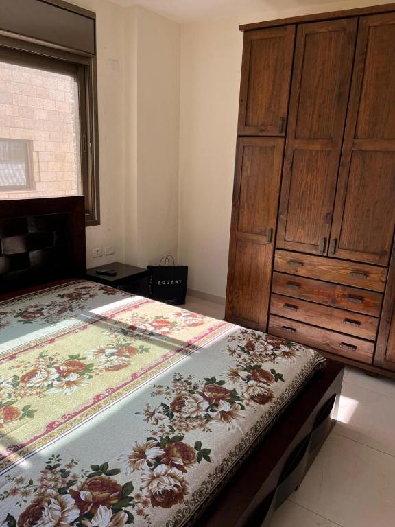 a bedroom with two beds and a wooden cabinet at Salah Khamlan Apartments in Nablus