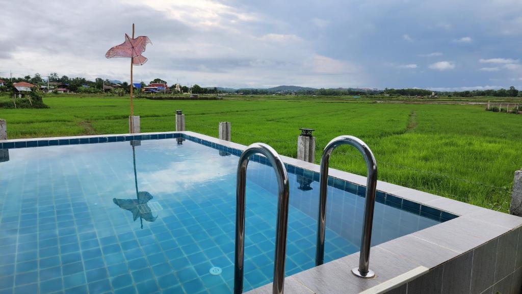 una piscina con vistas a un campo en บ้านกลางนาพูลวิลล่า en Nan