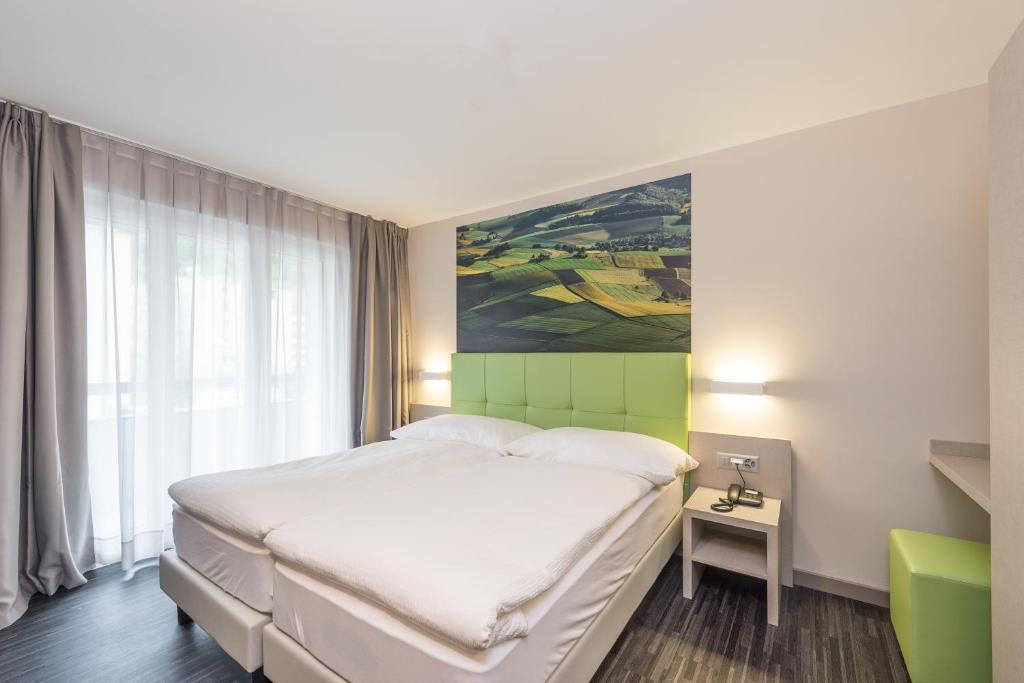 a bedroom with a bed and a painting on the wall at Adhhoc Hotel in Naters