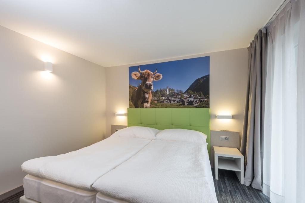 a bedroom with a bed with a picture of a cow on the wall at Adhhoc Hotel in Naters