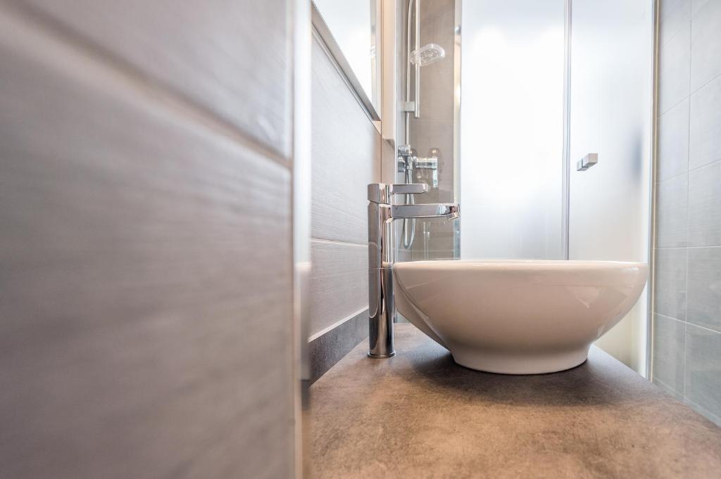 a white bathroom with a sink and a shower at Adhhoc Hotel in Naters