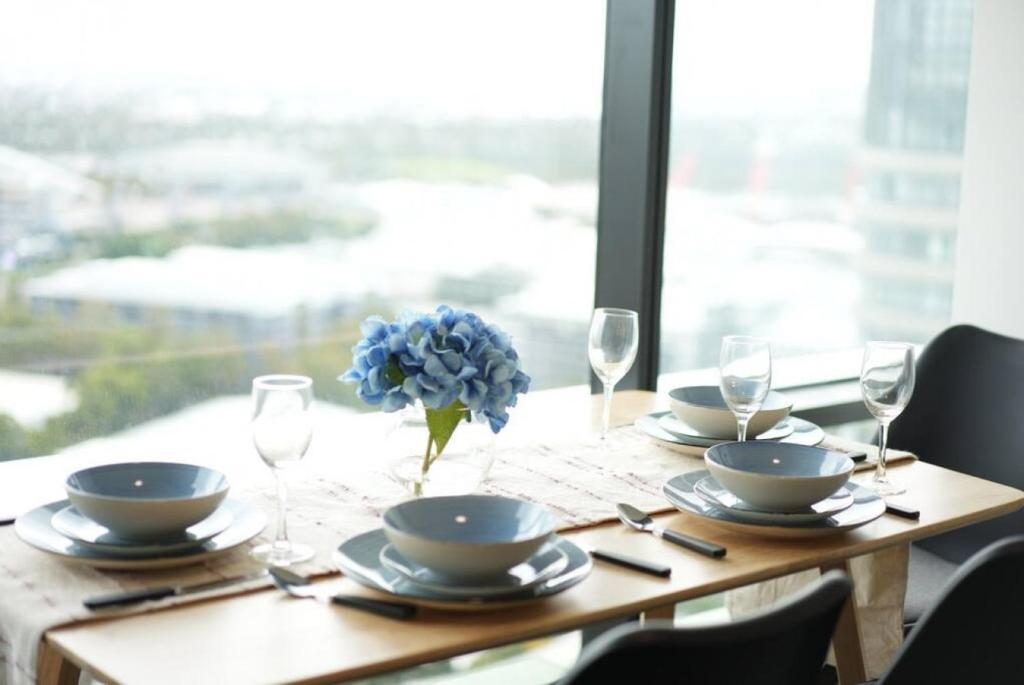雪梨的住宿－Superior View APT in heart of Sydney Olympic Park，一张桌子,上面有盘子和玻璃杯,上面有蓝色的花