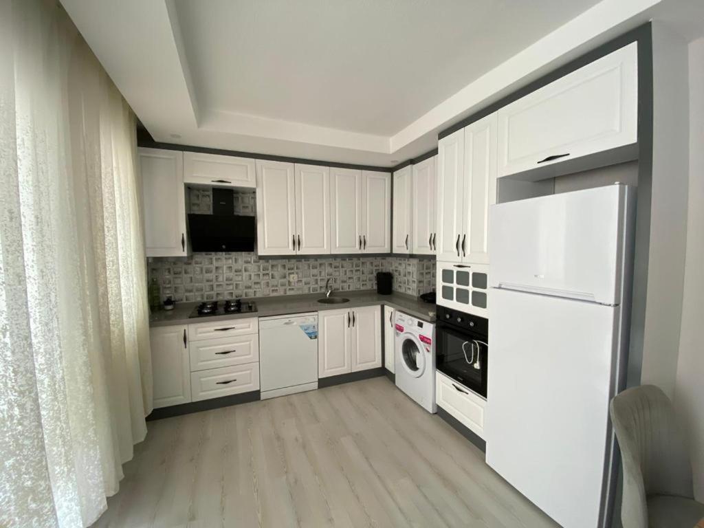 una cocina blanca con armarios y electrodomésticos blancos en 2+1 SÜPER EŞYALI KİRALIK DAİRE, en Dalaman