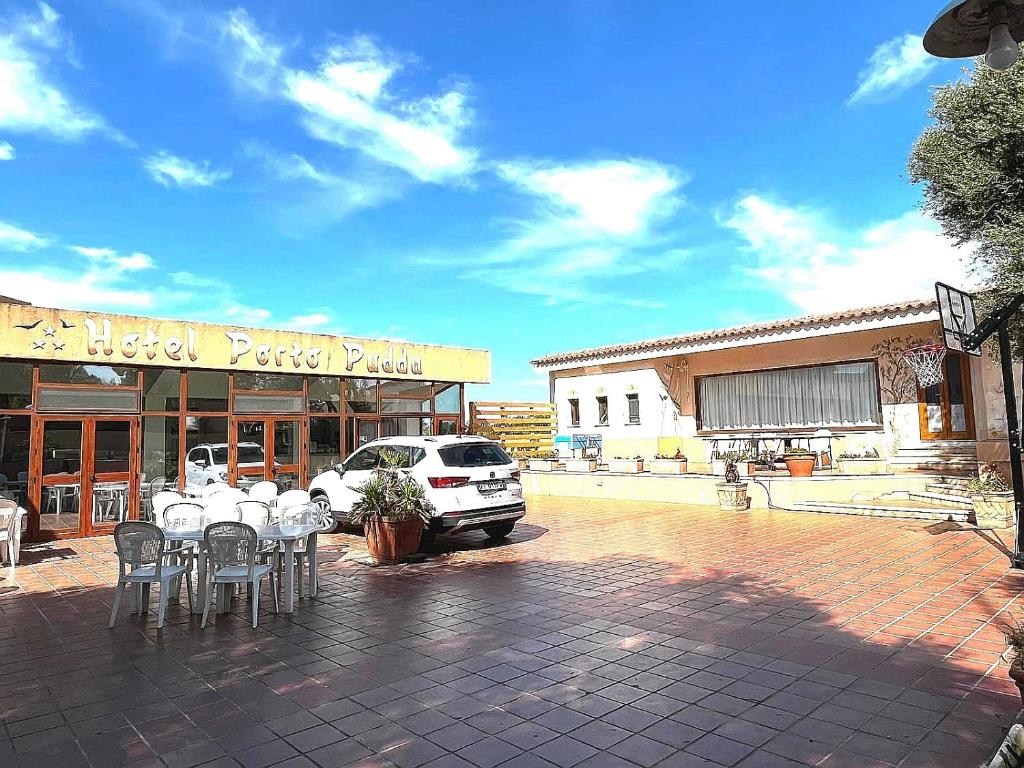 a parking lot with tables and chairs in front of a building at Hotel Porto Puddu - Il Nido dei Gabbiani in Porto Pollo