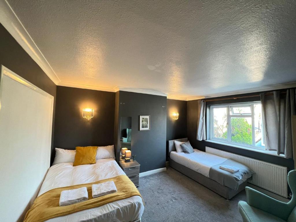 um quarto com 2 camas e uma janela em Airport Garden Rooms em Feltham