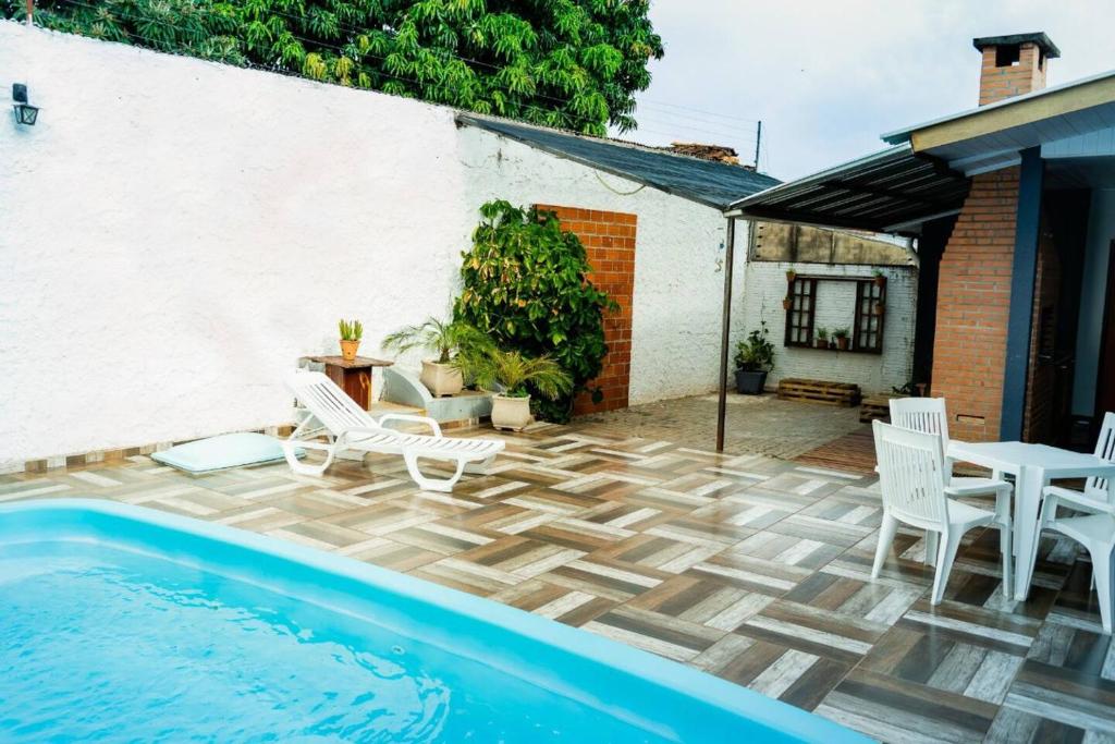 a patio with a pool and chairs and a table at Casa na Fronteira in Foz do Iguaçu