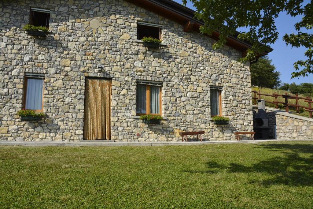 een stenen gebouw met deuren en ramen op een grasveld bij BAITA BELLAVISTA Affiliato Best-Incoming in Adrara San Rocco