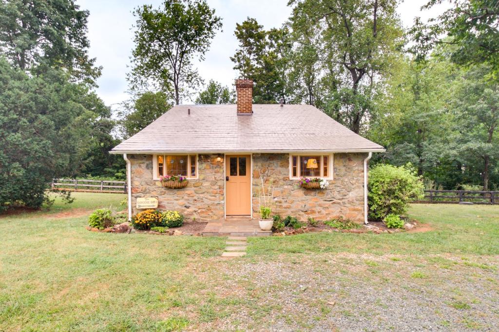 mały kamienny dom z pomarańczowymi drzwiami na polu w obiekcie Monticello Wine Trail Cottage - Close to Hiking! w mieście Afton