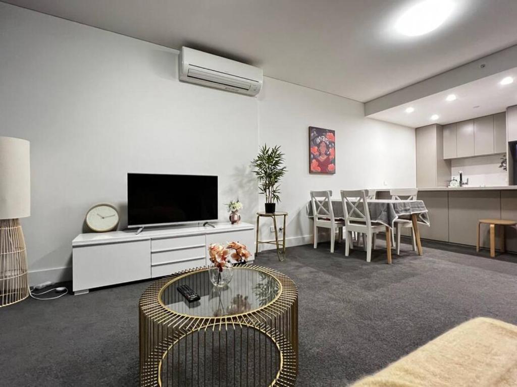 ein Wohnzimmer mit einem TV und einem Tisch in der Unterkunft Lovely 2 bedroom APT in centre of Olympic Park in Sydney
