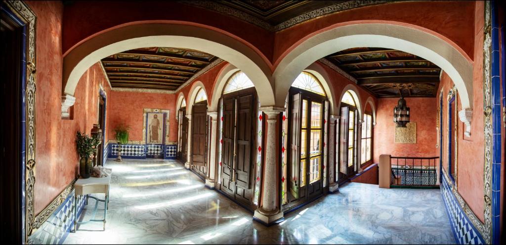 un corridoio di un vecchio edificio con archi e finestre di La casa del Cipres una casa con historia a Cordoba