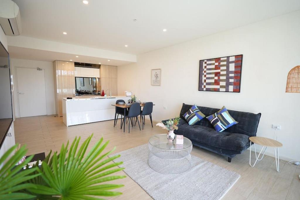 a living room with a black couch and a table at Stunning 2 bedroom APT in Wentworth point in Sydney