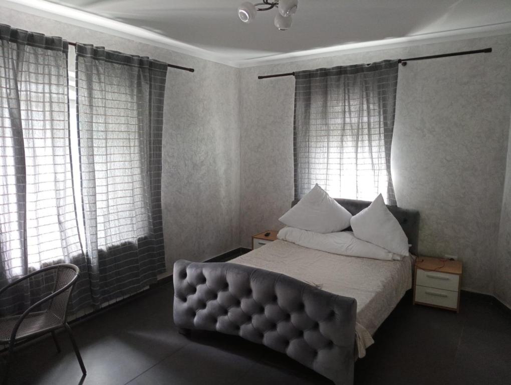 um quarto com uma cama, uma cadeira e janelas em Cataleya Caffee em Rădăuţi