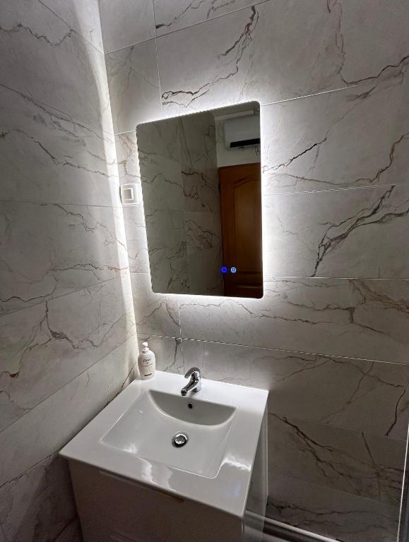 une salle de bain blanche avec un lavabo et un miroir dans l'établissement Hyper centre petit diamérisma, à Charleville-Mézières