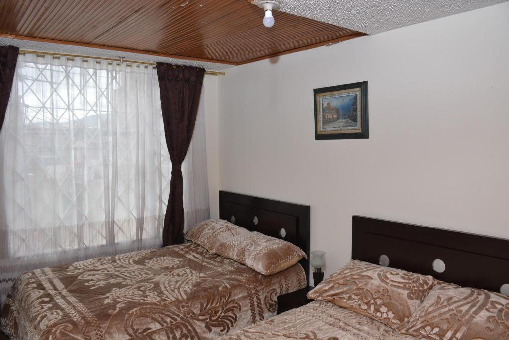 1 Schlafzimmer mit 2 Betten neben einem Fenster in der Unterkunft Habitacion # 2: Habitacion doble o triple in Sogamoso