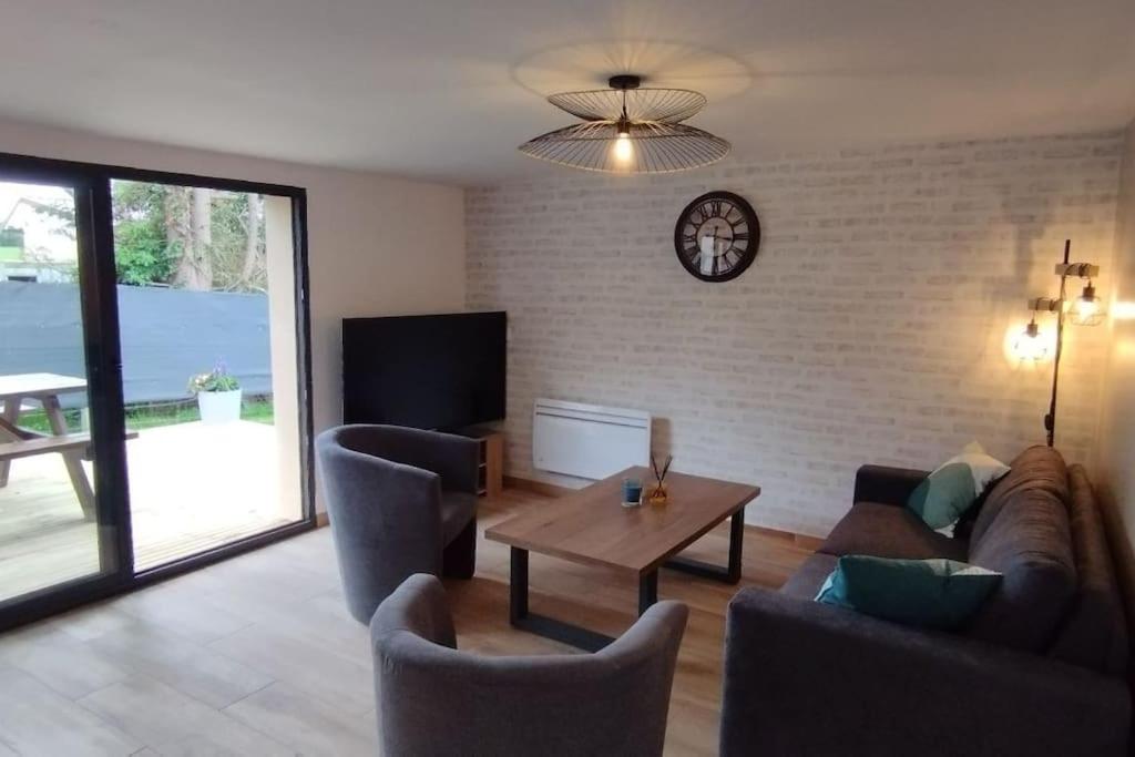 - un salon avec des canapés, une table et une horloge dans l'établissement Charmante maison de campagne, avec jardin, vue rivière, 15 min Cabourg, à Basseneville