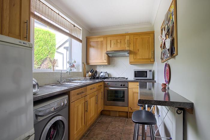 a kitchen with wooden cabinets and a sink and a dishwasher at Bar Cottage Number 2 in Altham