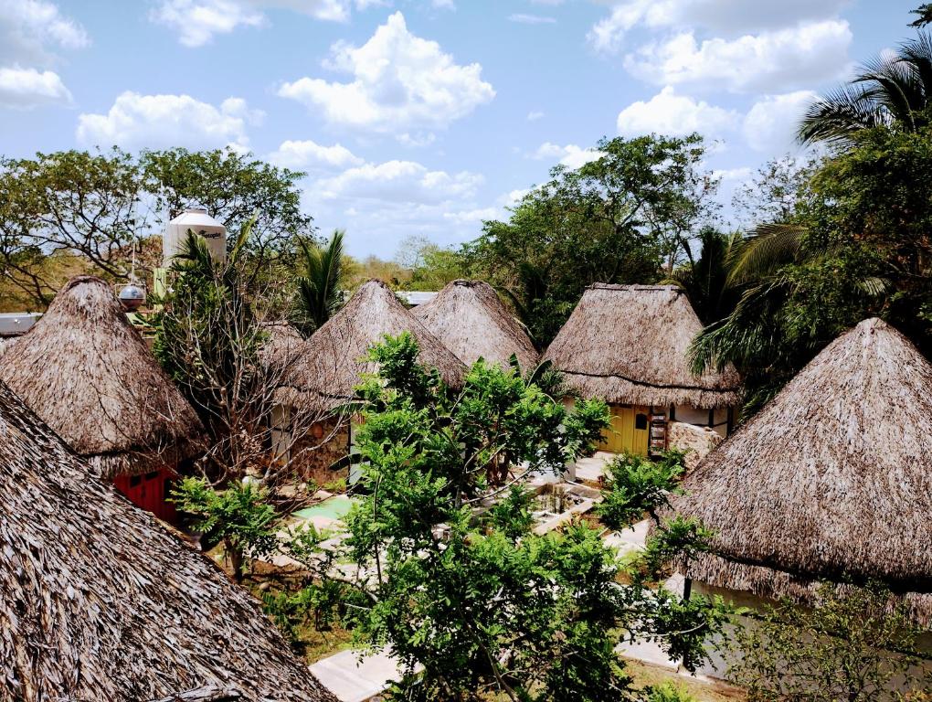 a group of houses with thatched roofs and trees at Aldea Maya Toktli Orígenes: Alberca + Wifi-Starlink + Tour Sustentabilidad in Izamal