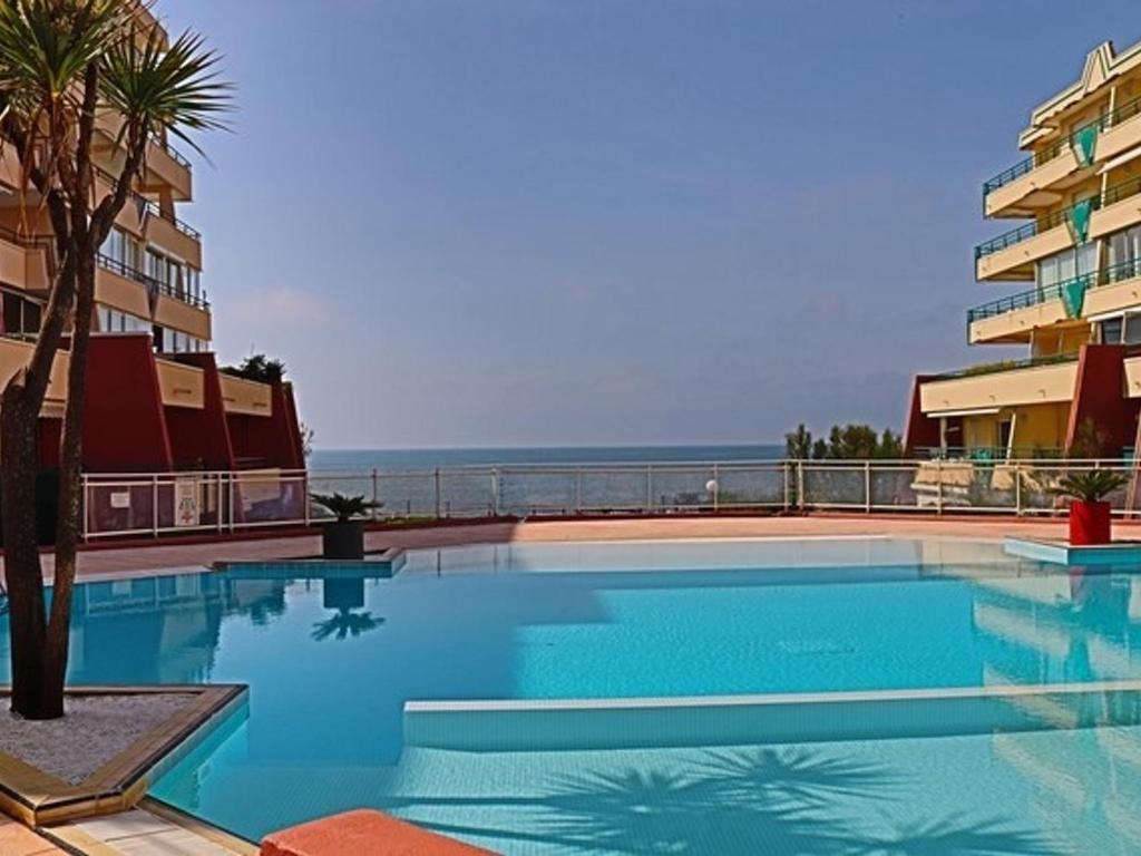 une grande piscine à côté d'un immeuble dans l'établissement Appartement 4 pers, piscine, parking, climatisation en bord de mer - FR-1-338-508, à Sète