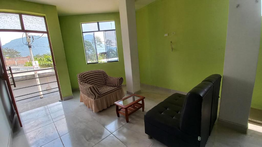 - un salon avec des murs verts, un canapé et une chaise dans l'établissement ALOJAMIENTO ANY, à Tingo María